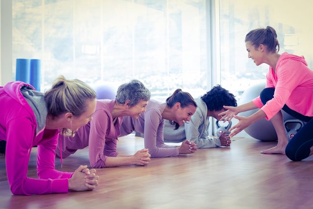 Smiling group of women exercising on floor in fitness studio